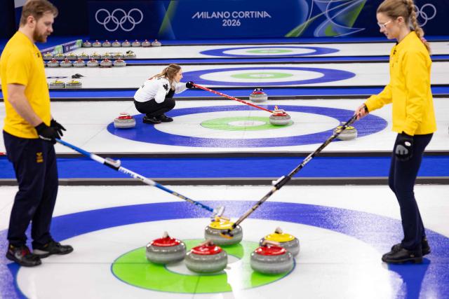 Canada's Jocelyn Peterman (C), Sweden's Isabella Wranaa (R) and Sweden's Rasmus Wranaa compete (L) react on the ice during the Milano Cortina 2026 Winter Olympic Games at the Cortina Curling Olympic Stadium in Cortina d’Ampezzo on February 7, 2026. (Photo by Odd ANDERSEN / AFP)