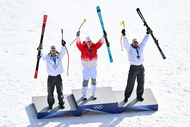 From (L-R) Italy's silver medalist Giovanni Franzoni,  Switzerland's gold medalist Franjo von Allmen and Italy's bronze medalist Dominik Paris celebrate on the podium after the men's downhill alpine skiing event during the Milano Cortina 2026 Winter Olympic Games at the Stelvio Ski Centre in Bormio (Valtellina) on February 7, 2026. (Photo by Fabrice COFFRINI / AFP)