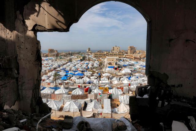 Tents sheltering Palestinians displaced by conflict are pictured by destroyed and heavily-damaged buildings in the Muqusi area of Gaza City on February 7, 2026. Since October 10, a fragile US-sponsored truce in Gaza has largely halted the fighting between Israeli forces and Hamas, but both sides have alleged frequent violations. (Photo by Omar AL-QATTAA / AFP)