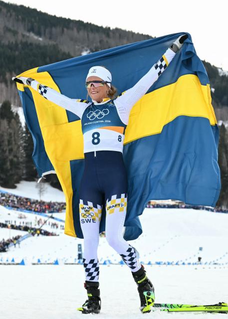 Sweden's Frida Karlsson holds Sweden's national flag  after winning the women's cross country 10km + 10km skiathlon event of the Milano Cortina 2026 Winter Olympic Games at Tesero Cross-Country Skiing Stadium in Lago di Tesero (Val di Fiemme) on February 7, 2026. (Photo by Javier SORIANO / AFP)