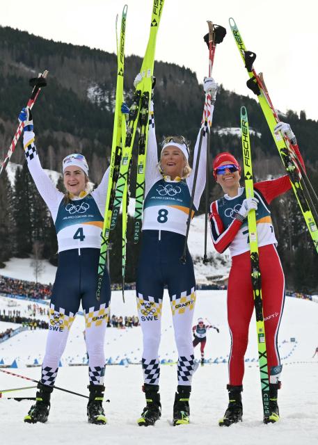 (From L) Silver medallist Sweden's Ebba Andersson, gold medallist Sweden's Frida Karlsson and bronze medallist Norway's Heidi Weng celebrate after the women's cross country 10km + 10km skiathlon event of the Milano Cortina 2026 Winter Olympics at Tesero Cross-Country Skiing Stadium in Lago di Tesero (Val di Fiemme) on February 7, 2026. (Photo by Javier SORIANO / AFP)