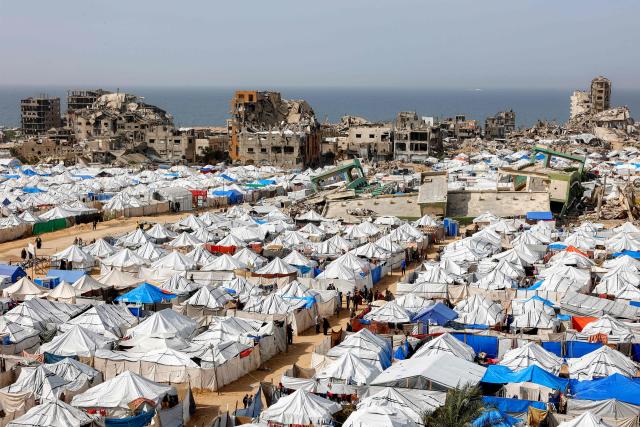 Tents sheltering Palestinians displaced by conflict are pictured by destroyed and heavily-damaged buildings in the Muqusi area of Gaza City on February 7, 2026. Since October 10, a fragile US-sponsored truce in Gaza has largely halted the fighting between Israeli forces and Hamas, but both sides have alleged frequent violations. (Photo by Omar AL-QATTAA / AFP)