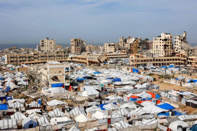 Tents sheltering Palestinians displaced by conflict are pictured by destroyed and heavily-damaged buildings in the Muqusi area of Gaza City on February 7, 2026. Since October 10, a fragile US-sponsored truce in Gaza has largely halted the fighting between Israeli forces and Hamas, but both sides have alleged frequent violations. (Photo by Omar AL-QATTAA / AFP)