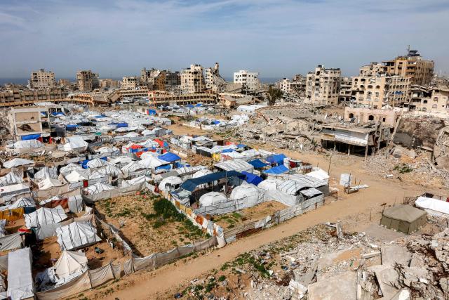 Tents sheltering Palestinians displaced by conflict are pictured by destroyed and heavily-damaged buildings in the Muqusi area of Gaza City on February 7, 2026. Since October 10, a fragile US-sponsored truce in Gaza has largely halted the fighting between Israeli forces and Hamas, but both sides have alleged frequent violations. (Photo by Omar AL-QATTAA / AFP)
