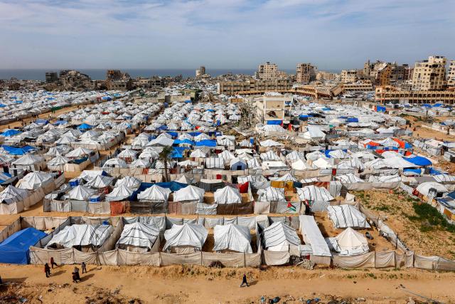 Tents sheltering Palestinians displaced by conflict are pictured by destroyed and heavily-damaged buildings in the Muqusi area of Gaza City on February 7, 2026. Since October 10, a fragile US-sponsored truce in Gaza has largely halted the fighting between Israeli forces and Hamas, but both sides have alleged frequent violations. (Photo by Omar AL-QATTAA / AFP)