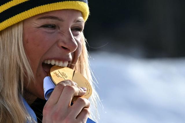 Gold medallist Sweden's Frida Karlsson celebrates on the podium for the women's cross country 10km + 10km skiathlon event of the Milano Cortina 2026 Winter Olympics at Tesero Cross-Country Skiing Stadium in Lago di Tesero (Val di Fiemme) on February 7, 2026. (Photo by Javier SORIANO / AFP)