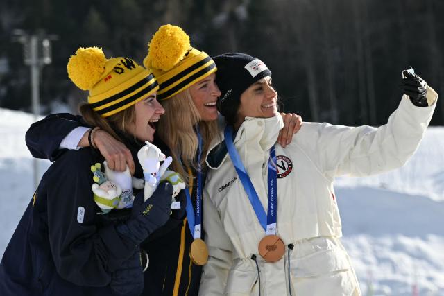 (From L) Silver medallist Sweden's Ebba Andersson, gold medallist Sweden's Frida Karlsson and bronze medallist Norway's Heidi Weng take a selfie photo as they celebrate on the podium for the women's cross country 10km + 10km skiathlon event of the Milano Cortina 2026 Winter Olympics at Tesero Cross-Country Skiing Stadium in Lago di Tesero (Val di Fiemme) on February 7, 2026. (Photo by Javier SORIANO / AFP)