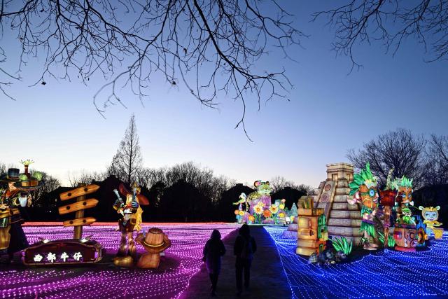 People walk past lantern decorations at the World Park in Beijing on February 7, 2026, ahead of the Lunar New Year. (Photo by ADEK BERRY / AFP)