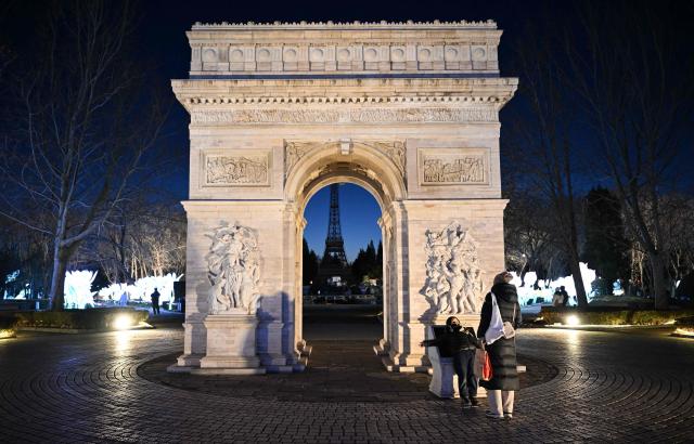 People stand near the replica of the Arc de Triomphe amid lantern decorations at the World Park in Beijing on February 7, 2026, ahead of the Lunar New Year. (Photo by ADEK BERRY / AFP)