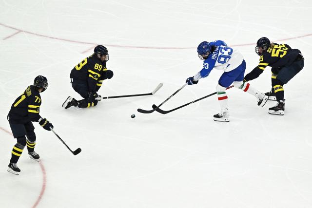 Italy's #93 Nadia Mattivi (2R) vies for the puck with Sweden's #89 Nicole Hall (2L) and Sweden's #55 Jenna Raunio (R) during the women's preliminary round Group B Ice Hockey match between Sweden and Italy at the Milano Santagiulia Ice Hockey Arena at the Milano Cortina 2026 Winter Olympic Games in Milan, on February 7, 2026. (Photo by JULIEN DE ROSA / AFP)