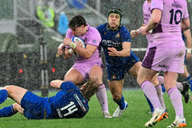 Scotland's full-back #15 Tom Jordan (C) is tackled by Italy's wing #14 Louis Lynagh (down) and Italy's reserve center #15 Leonardo Marin during the Six Nations international rugby union match between Italy and Scotland at the Stadio Olimpico, in Rome, on February 7, 2026. (Photo by Alberto PIZZOLI / AFP)
