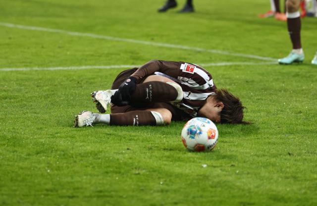 St Pauli's Japanese defender #15 Tomoya Ando reacts injured on the pitch during the German first division Bundesliga football match between St Pauli and VfB Stuttgart in Hamburg, northern Germany, on February 7, 2026. (Photo by Ibrahim OT / AFP) / DFL REGULATIONS PROHIBIT ANY USE OF PHOTOGRAPHS AS IMAGE SEQUENCES AND/OR QUASI-VIDEO