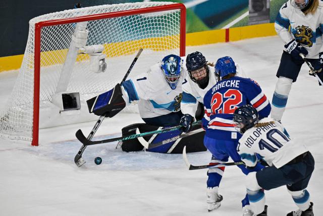 Finland's #01 Sanni Ahola (L) dives for the puck  during the women's preliminary round Group A Ice Hockey match between USA and Finland at the Milano Rho Ice Hockey Arena at the Milano Cortina 2026 Winter Olympic Games in Milan, on February 7, 2026. (Photo by Alexander NEMENOV / AFP)