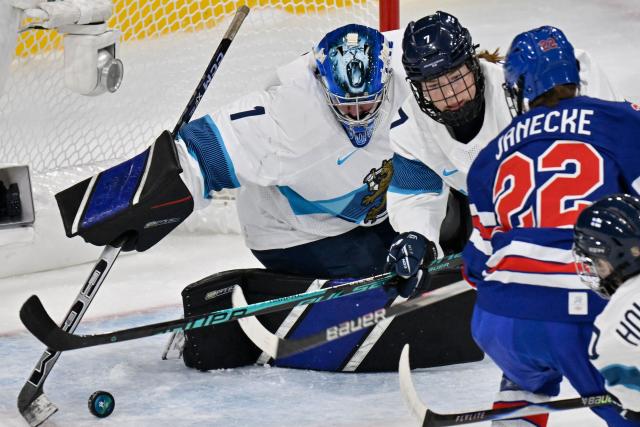 Finland's #01 Sanni Ahola (L) dives for the puck  during the women's preliminary round Group A Ice Hockey match between USA and Finland at the Milano Rho Ice Hockey Arena at the Milano Cortina 2026 Winter Olympic Games in Milan, on February 7, 2026. (Photo by Alexander NEMENOV / AFP)