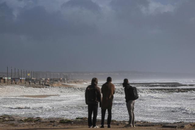 Some people observe from the promenade as Storm Marta whips up a rough sea in Costa da Caparica, Portugal, on February 7, 2026. Spain and Portugal today faced fresh storms and torrential rain just days after floods caused by Storm Leonardo proved fatal in both countries and caused significant damage. In Portugal, the latest depression -- christened Storm Marta -- has prompted the deployment of more than 26,500 rescuers and led three municipalities to postpone by a week a presidential vote meant to be held tomorrow. (Photo by PATRICIA DE MELO MOREIRA / AFP)