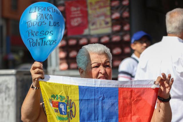 A family member holds a blue balloon reading "Freedom for all political prisoners" during a demonstration demanding the release of political prisoners in front of the El Helicoide building, headquarters of the Bolivarian National Intelligence Service (SEBIN), in Caracas on February 7, 2026. Venezuela's head of parliament on February 6 promised the speedy release of remaining political prisoners during a meeting with their relatives in which he promised to correct the government's "mistakes." (Photo by Pedro MATTEY / AFP)