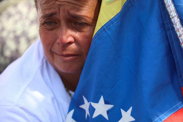 A family member holds a national flag during a demonstration demanding the release of political prisoners in front of the El Helicoide building, headquarters of the Bolivarian National Intelligence Service (SEBIN), in Caracas on February 7, 2026. Venezuela's head of parliament on February 6 promised the speedy release of remaining political prisoners during a meeting with their relatives in which he promised to correct the government's "mistakes." (Photo by Pedro MATTEY / AFP)
