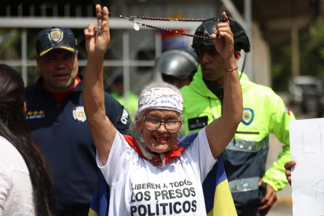 A family member holds a rosary during a demonstration demanding the release of political prisoners in front of the El Helicoide building, headquarters of the Bolivarian National Intelligence Service (SEBIN), in Caracas on February 7, 2026. Venezuela's head of parliament on February 6 promised the speedy release of remaining political prisoners during a meeting with their relatives in which he promised to correct the government's "mistakes." (Photo by Pedro MATTEY / AFP)