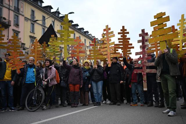 People attend a demonstration against the environmental, economic and social impact of the Milano-Cortina 2026 Winter Olympics Games, in Milan on February 7, 2026. The cardboard trees represent the larch trees cut to build the new sliding center in Cortina d'Ampezzo. (Photo by PIERO CRUCIATTI / AFP)