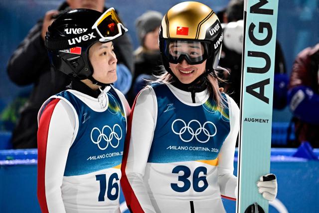 China's Liu Qi (L) and China's Zeng Ping react after competing during the women's ski jumping normal hill individual final round of the Milano Cortina 2026 Winter Olympic Games at Predazzo Ski Jumping Stadium in Predazzo (Val di Fiemme), on February 7, 2026. (Photo by Tobias SCHWARZ / AFP)