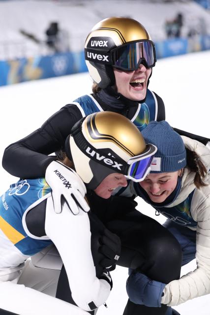 Norway's Eirin Maria Kvandal (L), gold medallist Norway's Anna Odine Stroem and Norway's Silje Opseth celebrate at the end of the women's ski jumping normal hill individual final round of the Milano Cortina 2026 Winter Olympic Games at Predazzo Ski Jumping Stadium in Predazzo (Val di Fiemme), on February 7, 2026. (Photo by Anne-Christine POUJOULAT / AFP)