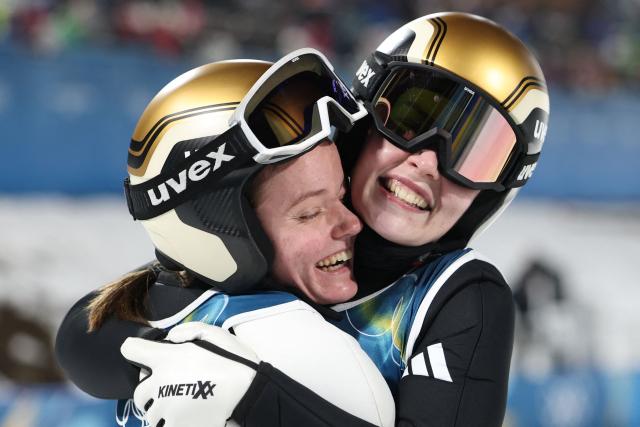 Norway's Eirin Maria Kvandal (L) celebrates with gold medallist Norway's Anna Odine Stroem at the end of the women's ski jumping normal hill individual final round of the Milano Cortina 2026 Winter Olympic Games at Predazzo Ski Jumping Stadium in Predazzo (Val di Fiemme), on February 7, 2026. (Photo by Anne-Christine POUJOULAT / AFP)