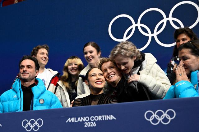 USA's Ilia Malinin (2R) hugs teammates USA's Madison Chock (2L) and USA's Evan Bates in the kiss and cry area after they competed in the figure skating team event ice dance-free dance during the Milano Cortina 2026 Winter Olympic Games at Milano Ice Skating Arena in Milan on February 7, 2026. (Photo by WANG Zhao / AFP)