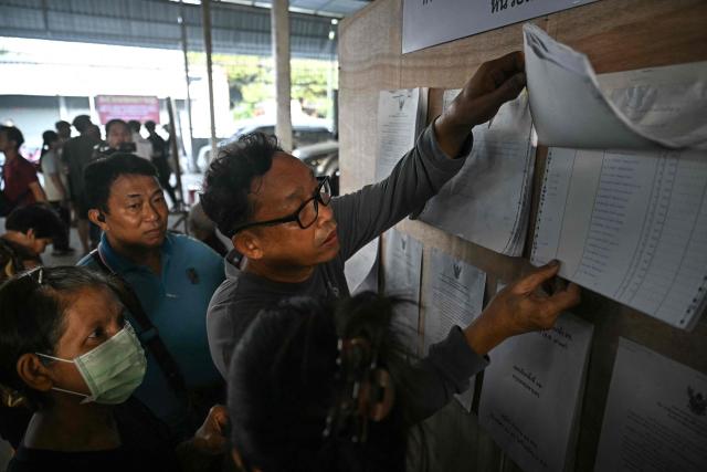 People look for their names on the voter registration sheets as polls open in Thailand's general election at a polling station in Bangkok on February 8, 2026. (Photo by Lillian SUWANRUMPHA / AFP)
