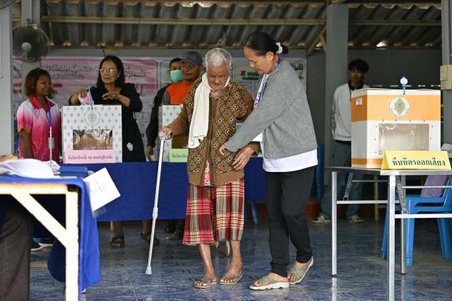 A voter is assisted as after casting her ballot in Thailand's general election in Buriram on February 8, 2026. Voting opened on February 8 in a Thai general election pitting the popular reformists who came first last time against the conservative who ended up as prime minister, with ex-leader Thaksin Shinawatra looming large from his prison cell. (Photo by ANTHONY WALLACE / AFP)