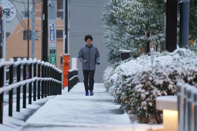 A runner jogs in the snow during the early morning in Tokyo on February 8, 2026. (Photo by Kazuhiro NOGI / AFP)