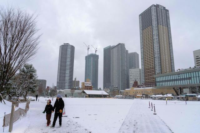 A family visits a snow-covered park in the early morning in Tokyo on February 8, 2026. (Photo by Kazuhiro NOGI / AFP)