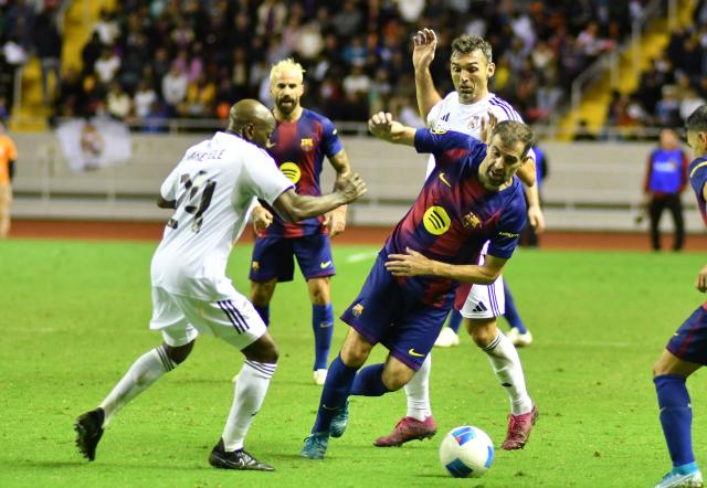Real Madrid's French midfielder Claude Makelele (L) and Barcelona's Spanish defender Fernando Navarro (R) fight for the ball during the exhibition friendly football match between Spain's Real Madrid Legends and Barcelona Legends at the National Stadium in San Jose on February 7, 2026. (Photo by Ezequiel BECERRA / AFP)