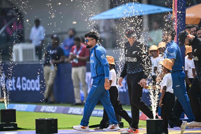 Afghanistan's captain Rashid Khan (L) enters the pitch with his New Zealand counterpart Mitchell Santner (2L) before the start of the 2026 ICC Men's T20 Cricket World Cup group stage match between Afghanistan and New Zealand at the MA Chidambaram Stadium in Chennai on February 8, 2026. (Photo by R. Satish BABU / AFP)