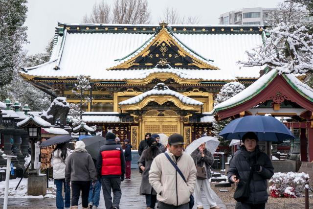 Tourists visit Toshogu Shrine in Ueno Park during a snowfall in Tokyo on February 8, 2026. (Photo by Kazuhiro NOGI / AFP)