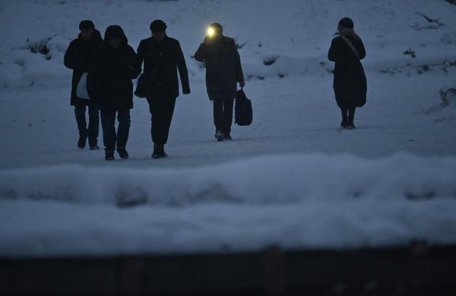 A pedestrian uses his phone's flashlight for visibility in the centre of Kyiv during blackout hours on February 7, 2026, amid the Russian invasion of Ukraine. (Photo by Sergei SUPINSKY / AFP)