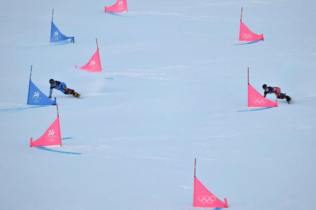 Switzerland's Julie Zogg (R) and Italy's Lucia Dalmasso (L) compete in the snowboard women's parallel giant slalom qualification run at Livigno Snow Park during the Milano Cortina 2026 Winter Olympic Games, in Livigno (Valtellina), on February 8, 2026. (Photo by Jeff PACHOUD / AFP)