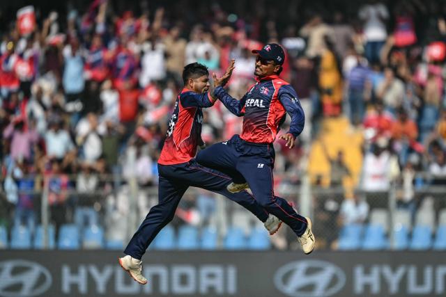 Nepal's Sandeep Lamichhane (L) celebrates with captain Rohit Paudel after taking the wicket of England's Tom Banton during the 2026 ICC Men's T20 Cricket World Cup group stage match between England and Nepal at the Wankhede Stadium in Mumbai on February 8, 2026. (Photo by Indranil MUKHERJEE / AFP)