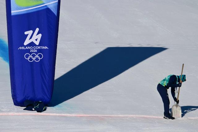 A course worker shovels snow at the finish line before the women's downhill event during the Milano Cortina 2026 Winter Olympic Games at the Tofane Alpine Skiing Centre in Cortina d’Ampezzo on February 8, 2026. (Photo by Stefano RELLANDINI / AFP)