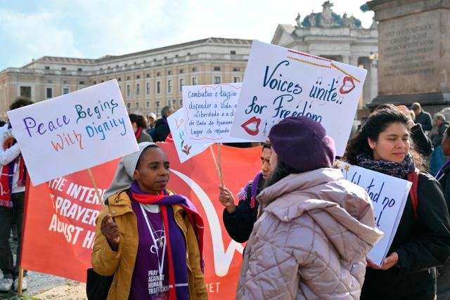 People hold placards to mark the International Day of prayer and awarness against Human Trafficking before at St. Peter's square before the Angelus prayer in The Vatican on February 8, 2026. (Photo by Alberto PIZZOLI / AFP)