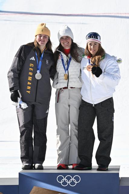 Gold medallist US' Breezy Johnson (C), silver medallist Germany's Emma Aicher (L) and bronze medallist Italy's Sofia Goggia (R) pose on the podium of the women's downhill event during the Milano Cortina 2026 Winter Olympic Games at the Tofane Alpine Skiing Centre in Cortina d’Ampezzo on February 8, 2026. (Photo by Tiziana FABI / AFP)