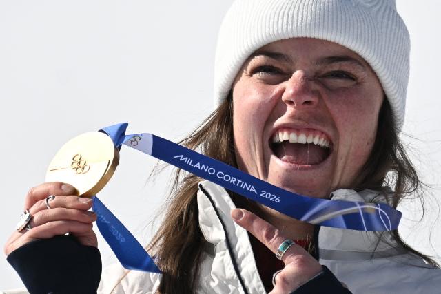 Gold medallist US' Breezy Johnson poses on the podium of the women's downhill event during the Milano Cortina 2026 Winter Olympic Games at the Tofane Alpine Skiing Centre in Cortina d’Ampezzo on February 8, 2026. (Photo by Tiziana FABI / AFP)