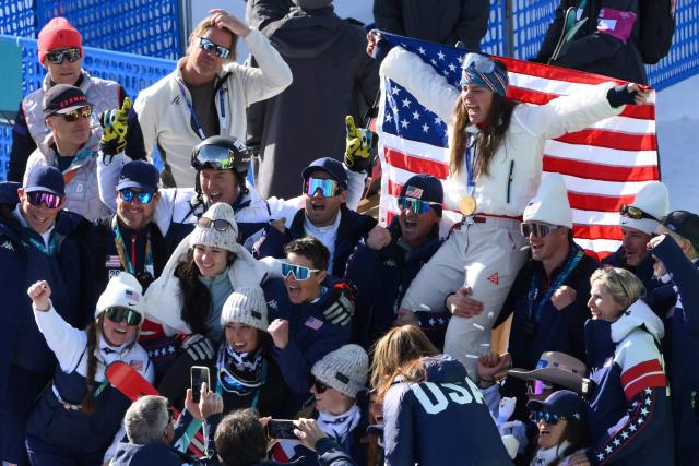 Gold medallist US' Breezy Johnson poses with her team after the podium ceremony of the women's downhill event during the Milano Cortina 2026 Winter Olympic Games at the Tofane Alpine Skiing Centre in Cortina d’Ampezzo on February 8, 2026.  (Photo by Marco BERTORELLO / AFP)