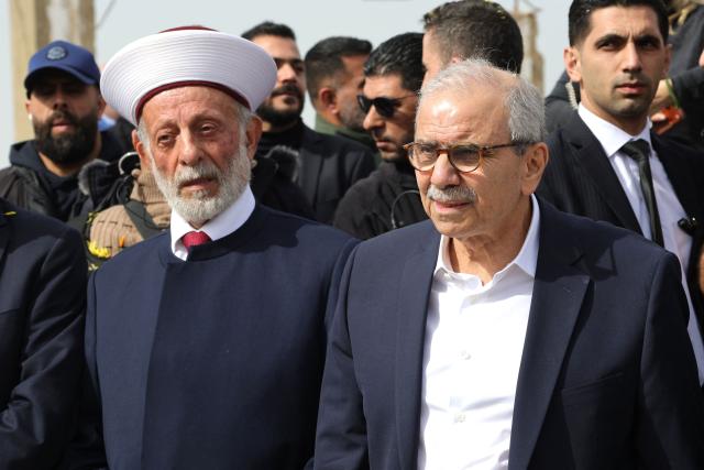 Judicial Muslim Mufti of the southern Lebanese towns of Marjayoun and Hasbaya Hassan Dali (L) stands along side Lebanon's Prime Minister Nawaf Salam during his visit to the heavily-damaged southern village of Kfar Shouba, near the border with Israel on February 8, 2026. Swathes of south Lebanon's border areas remain in ruins and largely deserted more than a year after a US-brokered November 2024 ceasefire sought to end hostilities between Israel and the Iran-backed group. Salam vowed authorities would begin key projects including restoring roads, communications networks and water in the two towns (Photo by Rabih DAHER / AFP)