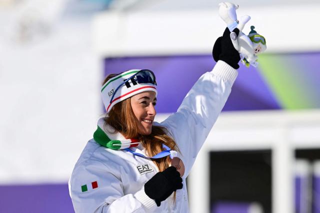 Italy's Sofia Goggia holds up her bronze medal on the podium of the women's downhill event during the Milano Cortina 2026 Winter Olympic Games at the Tofane Alpine Skiing Centre in Cortina d’Ampezzo on February 8, 2026. (Photo by Stefano RELLANDINI / AFP)