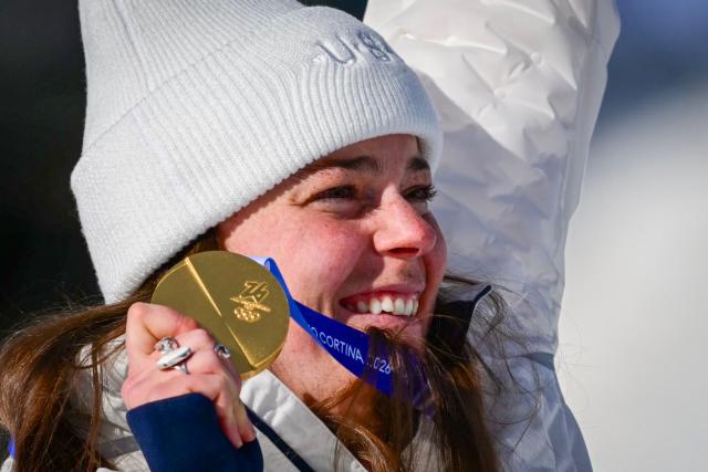 US' Breezy Johnson holds up her gold medal on the podium of the women's downhill event during the Milano Cortina 2026 Winter Olympic Games at the Tofane Alpine Skiing Centre in Cortina d’Ampezzo on February 8, 2026. (Photo by Stefano RELLANDINI / AFP)