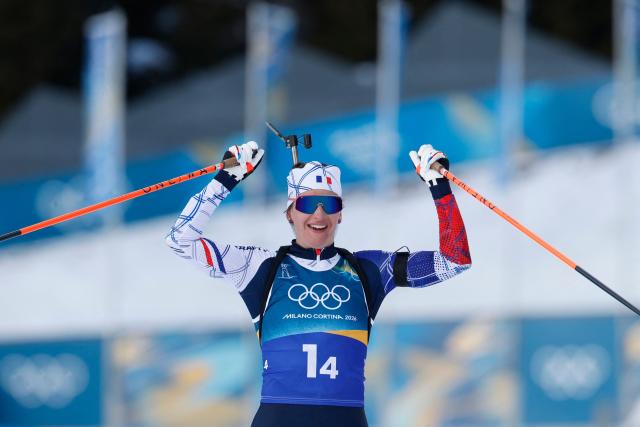 France's Julia Simon celebrates as she crosses the finish line for France to win gold in the mixed biathlon 4 x 6km relay event during the Milano Cortina 2026 Winter Olympic Games at the Anterselva Biathlon Arena (Sudtirol Arena) in Anterselva (Val Pusteria) on February 8, 2026. (Photo by Odd ANDERSEN / AFP)
