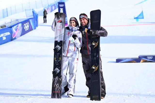 Silver medallist Austria's Sabine Payer (L) and gold medallist Austria's Benjamin Karl (R) pose with their medals after the snowboard men's and women's parallel giant slalom final at Livigno Snow Park during the Milano Cortina 2026 Winter Olympic Games, in Livigno (Valtellina), on February 8, 2026. (Photo by Kirill KUDRYAVTSEV / AFP)