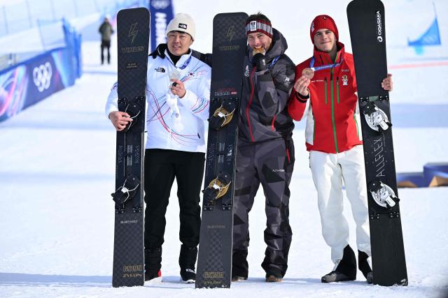 (From L) Silver medallist South Korea's Kim Sangkyum, gold medallist Austria's Benjamin Karl and bronze-medallist Bulgaria's Tervel Zamfirov celebrate on the podium after the snowboard men's parallel giant slalom final at Livigno Snow Park during the Milano Cortina 2026 Winter Olympic Games, in Livigno (Valtellina), on February 8, 2026. (Photo by Kirill KUDRYAVTSEV / AFP)