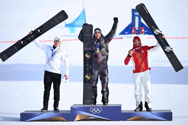 (From L) Silver medallist South Korea's Kim Sangkyum, gold medallist Austria's Benjamin Karl and bronze-medallist Bulgaria's Tervel Zamfirov celebrate on the podium after the snowboard men's parallel giant slalom final at Livigno Snow Park during the Milano Cortina 2026 Winter Olympic Games, in Livigno (Valtellina), on February 8, 2026. (Photo by Kirill KUDRYAVTSEV / AFP)