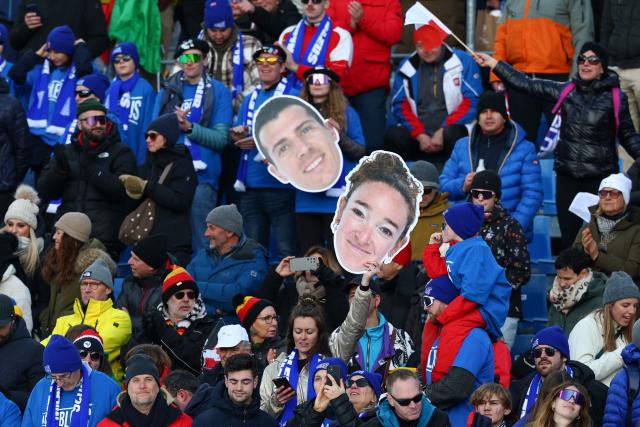 French spectators hold a cardboard cut out of the face of France's Lou Jeanmonnot (C) in the mixed biathlon 4 x 6km relay event during the Milano Cortina 2026 Winter Olympic Games at the Anterselva Biathlon Arena (Sudtirol Arena) in Anterselva (Val Pusteria) on February 8, 2026. (Photo by FRANCK FIFE / AFP)